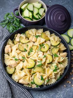 pasta with zucchini, chicken and parsley in a bowl next to sliced cucumbers