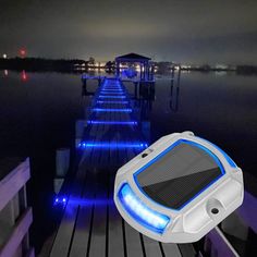 a solar powered device is sitting on a dock at night with blue lights around it