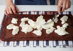 a person is spreading icing on top of a chocolate cake with marshmallows