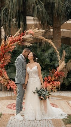 a bride and groom are standing in front of an archway with palm trees behind them