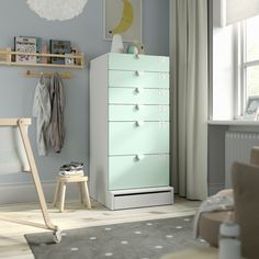 a baby's room with a green dresser in the corner