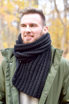 a man wearing a black knitted scarf and green jacket with his hands in his pockets