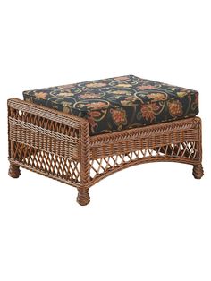 a wicker footstool with a floral seat cushion on it's side