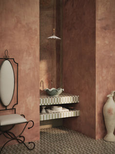 a bathroom with pink walls and tiled flooring next to a white vase on the counter