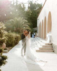 a bride and groom kissing in front of an outdoor ceremony venue with string lights hanging from the ceiling