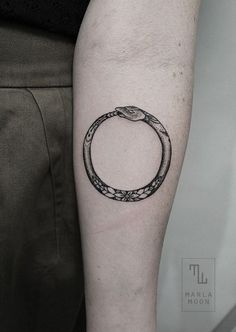 a black and white photo of a snake in a circle tattoo on the right arm