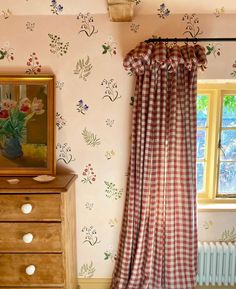 the curtains are hanging in front of the window with flowers on it and an old dresser