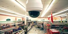 a camera mounted to the side of a ceiling in a store with lots of shelves