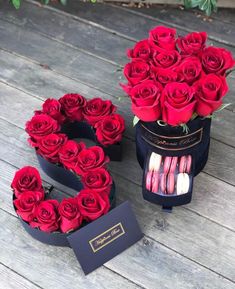 two boxes with roses and macaroons in them sitting on a wooden floor next to each other