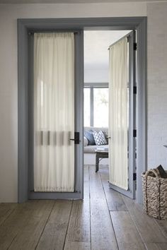 an open door leading to a living room with white walls and wood floors, along with a basket on the floor