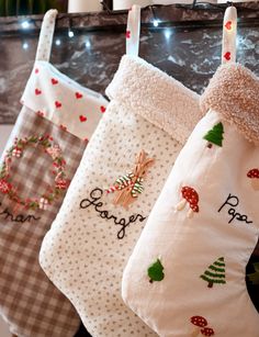 three christmas stockings hanging on a rack with lights in the background and decorations around them