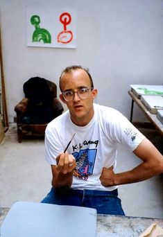 a man sitting at a table with a pen in his hand and another person behind him