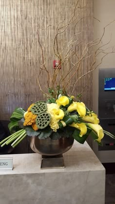 a vase filled with yellow flowers sitting on top of a white table next to a sign