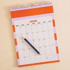 an orange and pink calendar with a pen on it