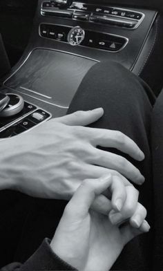 two hands on the steering wheel of a car, one holding the other's hand