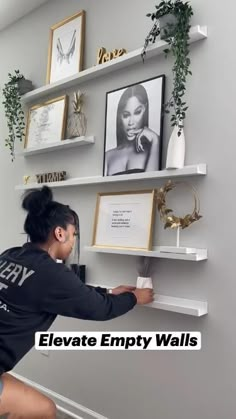 a woman is placing pictures on the wall