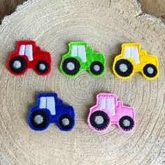 four different colored tractors are on a tree stump, one is black and the other is red