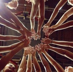 a group of people standing in a circle with their hands on top of each other