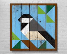 a wooden wall hanging on the side of a brick building with an abstract geometric design