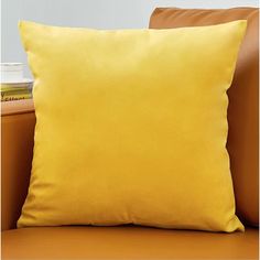 a yellow pillow sitting on top of a brown couch