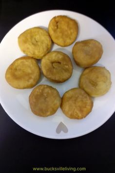 a white plate topped with fried pastries on top of a black tablecloth next to a knife and fork