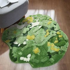 a green rug with yellow and white flowers on the floor next to a gray chair