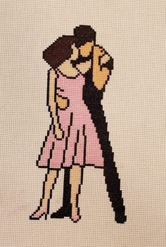 a cross stitch picture of a man and woman hugging in front of a white background