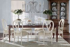 a dining room table with white chairs and chandelier