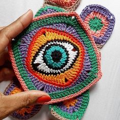 someone is holding up some crocheted coasters with an evil eye on them