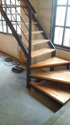 a set of stairs in an empty room next to a window with wires on the floor