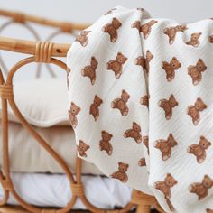 a baby crib with white sheets and brown teddy bears on it's sides