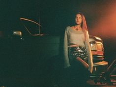 a woman standing next to a car in the dark