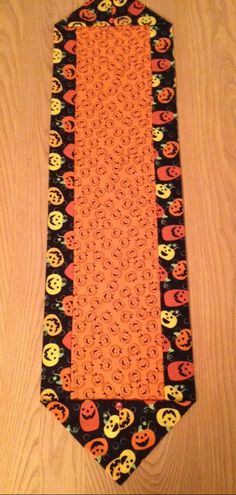 a neck tie decorated with pumpkins and skulls on a wooden surface, as if for halloween