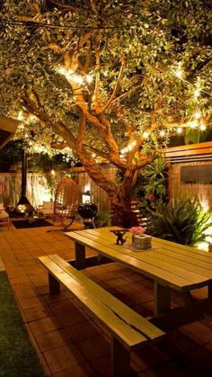 a wooden table sitting under a tree covered in lights