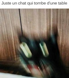 blurry photograph of black shoes in front of wooden cupboards, with one person's feet on the floor