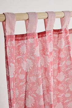 pink curtains hanging from a wooden rod in front of a white wall