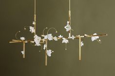 a chandelier with white flowers hanging from it's sides and wooden poles