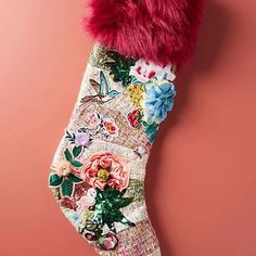 a christmas stocking hanging on a pink wall with flowers and leaves painted on it