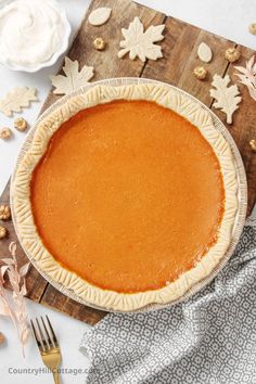 a pumpkin pie sitting on top of a wooden cutting board