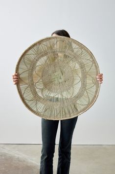 a woman is holding up a large woven basket in front of her face and back to the camera