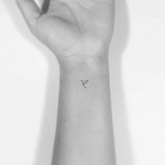 a small tattoo on the wrist of a woman's arm, with a bird flying above it