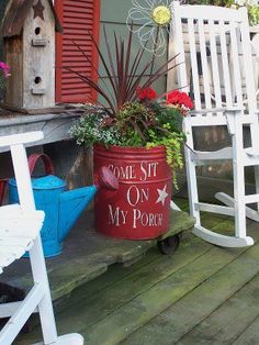 a white rocking chair sitting on top of a porch next to a potted plant