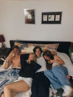 a group of people laying on top of a bed next to each other in a bedroom