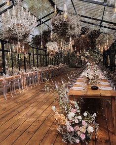 a long table with clear chairs and chandeliers hanging from it's ceiling