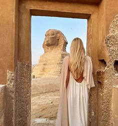 a woman standing in front of the sphinxs at giza, with her back to the camera