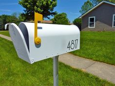 a white mailbox sitting on the side of a road next to a grass covered yard