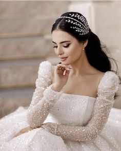 a woman in a white dress is sitting on the stairs and wearing a tiara