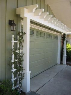 a white trellis on the side of a house next to a green garage door