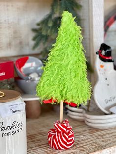 a small green christmas tree sitting on top of a table next to a can of soda