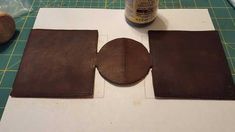 a piece of leather sitting on top of a cutting board next to a bottle of glue